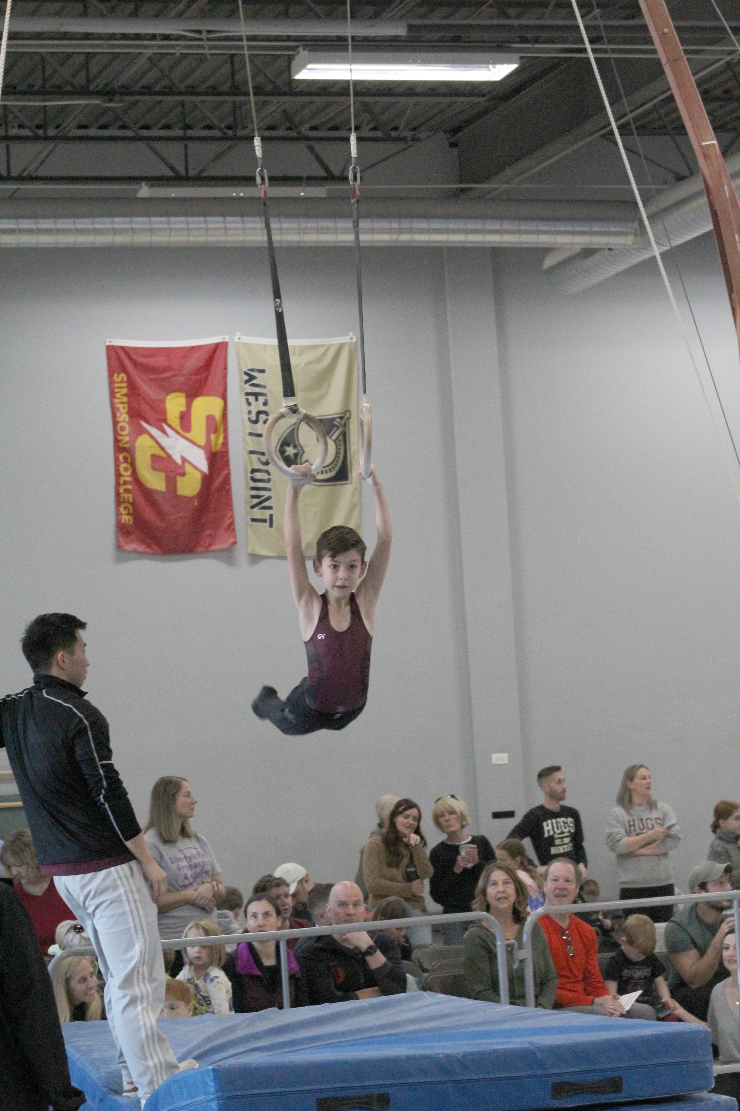 Young gymnast performing on rings at a competition