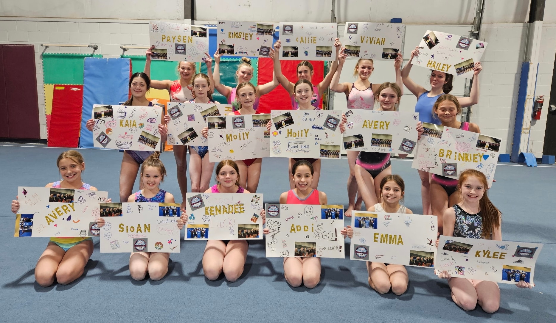 Huntley Unlimited Gymnastics team holding personalized good luck signs