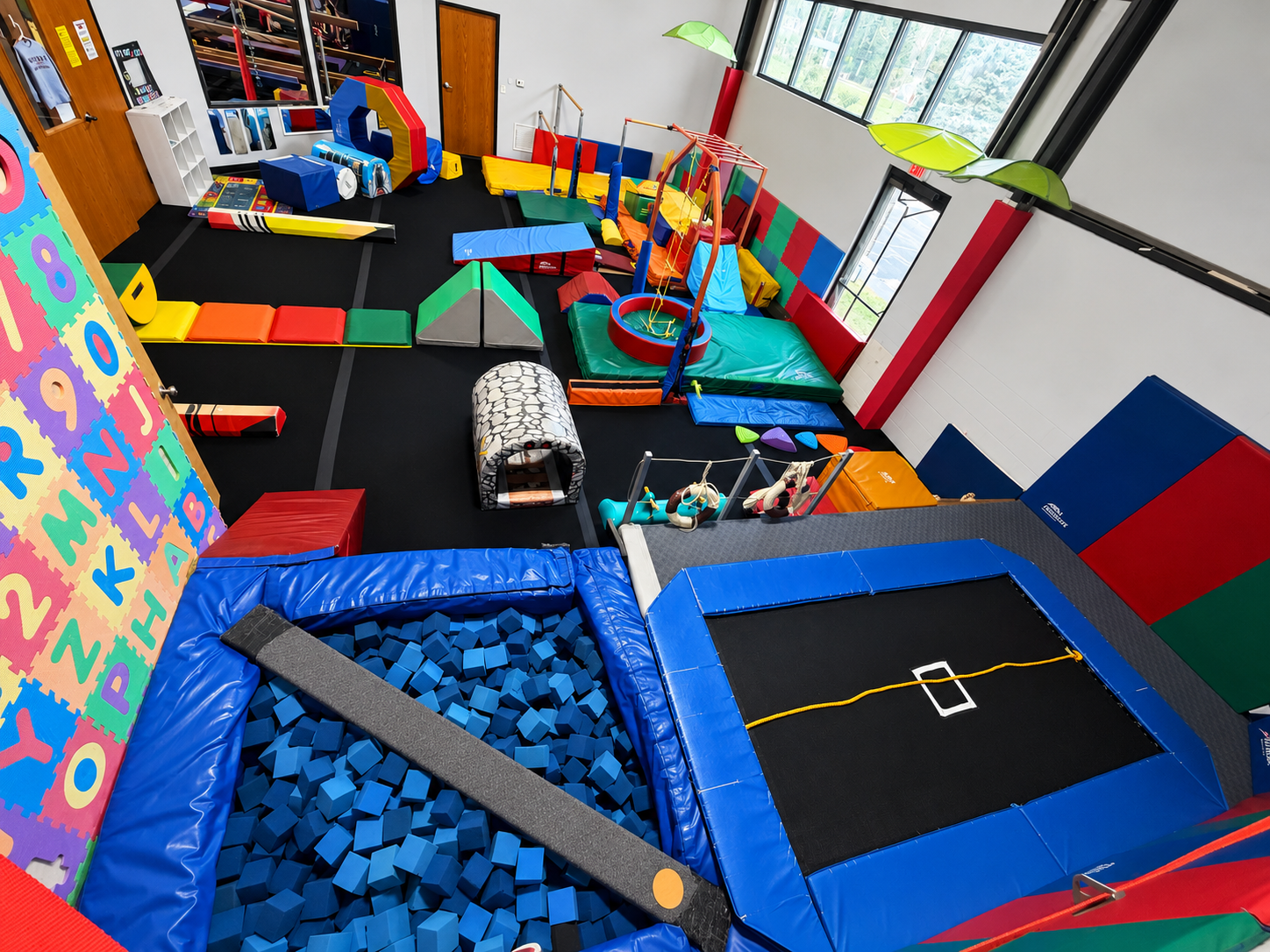 Overhead view of the H.U.G.S. tots gym floor with foam pit, trampoline, tunnels, and colorful equipment